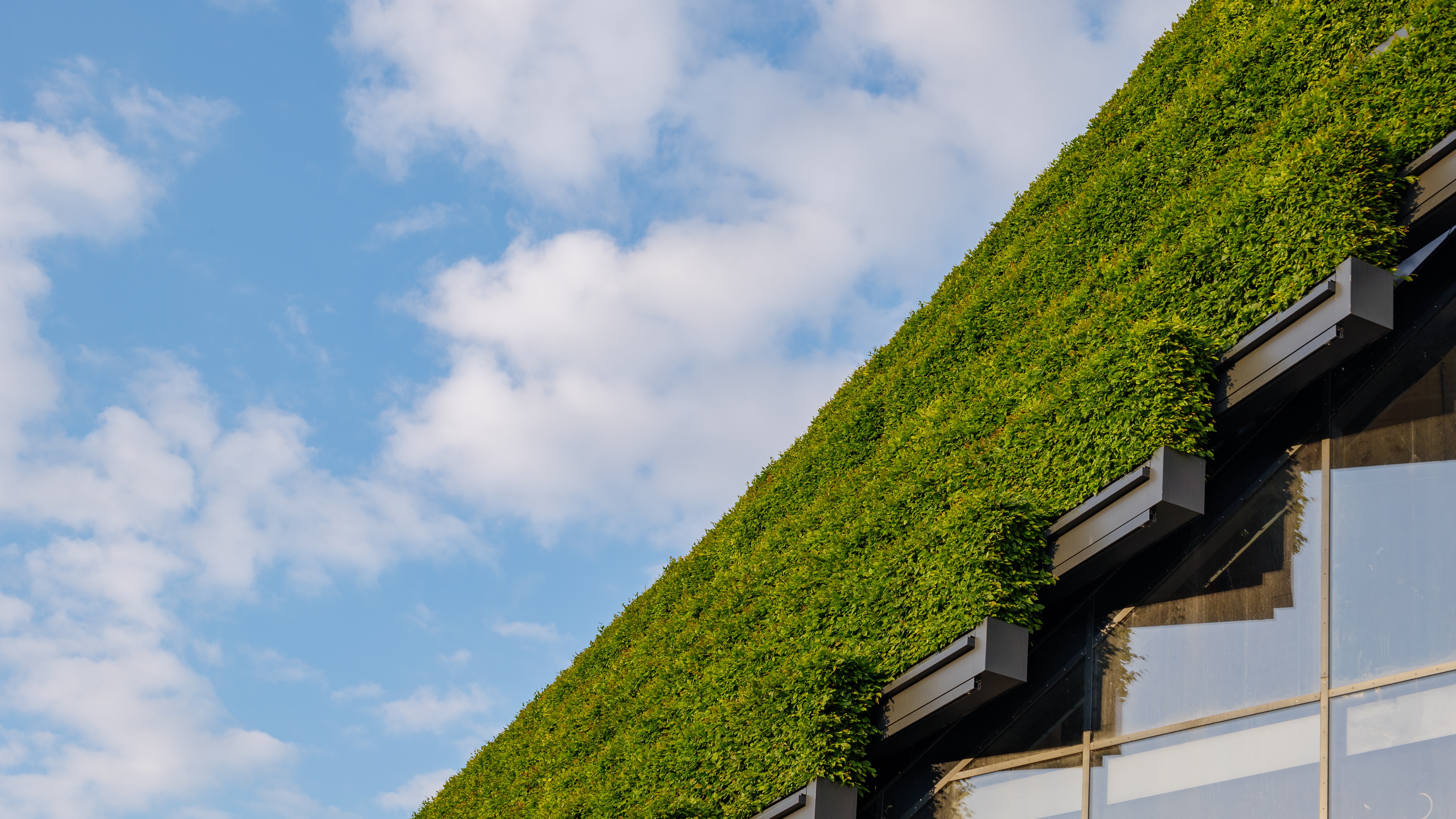 A green-roofed building with reflective glass windows illustrates Apollo’s sustainable approach to real assets, private credit, and capital solutions.