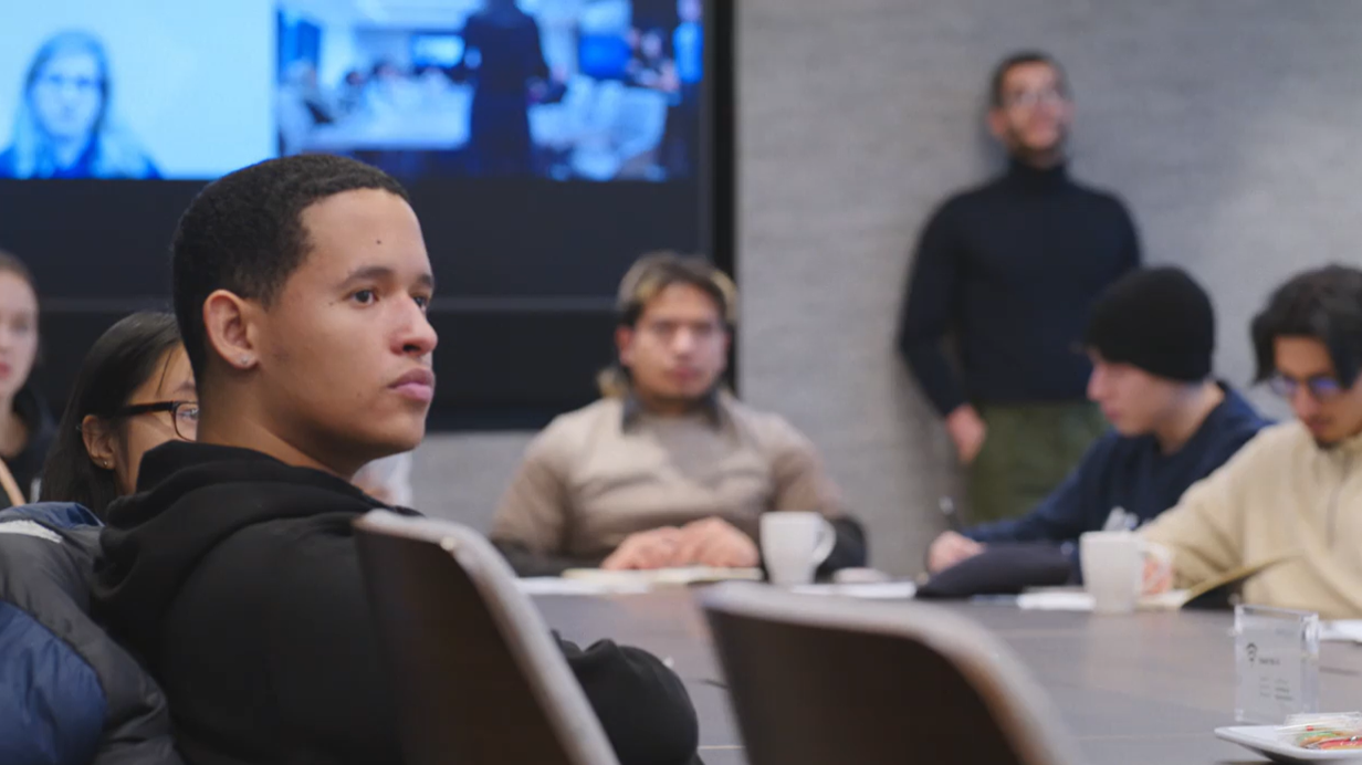 Group of young people seated in chairs with one person standing against a wall, captured during Apollo Opportunity Foundation’s anniversary event celebrating community impact.