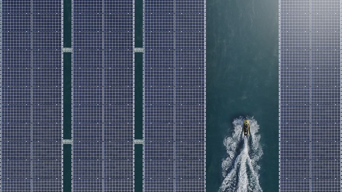 Aerial view of a motorboat moving between floating solar panels on water, symbolizing how private capital can accelerate renewable energy innovation and power the future through bold, agile infrastructure investment.